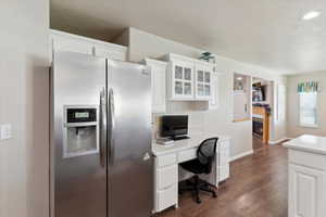 Kitchen featuring stainless steel refrigerator with ice dispenser, a textured ceiling, dark wood-type flooring, light countertops, and white cabinetry