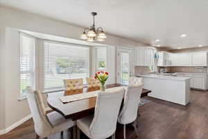 Dining space with a chandelier, dark wood-type flooring, recessed lighting, and baseboards
