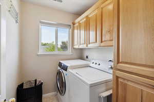 Washroom featuring cabinet space, washer and dryer, and baseboards