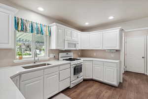Kitchen featuring white appliances, a sink, white cabinetry, light countertops, and recessed lighting