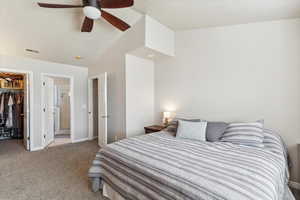 Bedroom featuring a walk in closet, a closet, carpet flooring, baseboards, and a ceiling fan