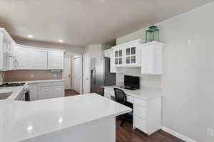 Kitchen with white appliances, dark wood-type flooring, white cabinetry, a desk, and recessed lighting