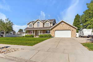 Traditional home featuring covered porch, an attached garage, driveway, and brick siding
