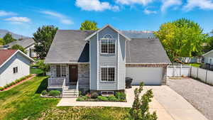 View of front of house featuring covered porch, driveway, a mountain view, an attached garage, and stone siding