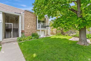 View of grassy yard with a balcony