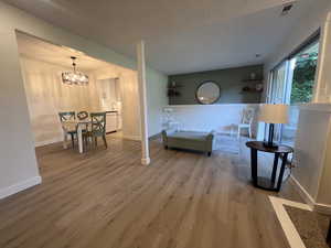 Living area with wood finished floors, a textured ceiling, and a chandelier