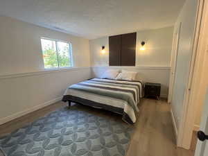 Bedroom with wood finished floors and a textured ceiling