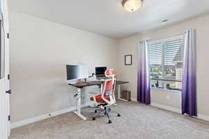 Office space/bedroom featuring carpet flooring and baseboards