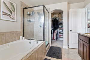 Full bathroom with a bath, a stall shower, vanity, a walk in closet, and tile patterned floors