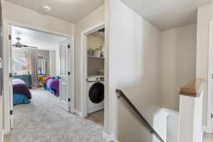 Hall featuring washer / dryer, an upstairs landing, carpet, and baseboards