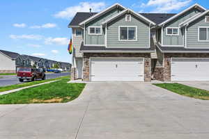 Craftsman-style home with board and batten siding, stone siding, an attached garage, driveway, and a residential view