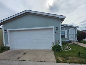Single story home with driveway, a front lawn, and a garage