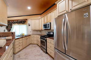 Kitchen with stainless steel appliances, light brown cabinetry, a sink, recessed lighting, and tile countertops