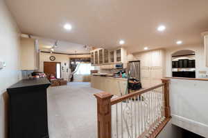 Kitchen with freestanding refrigerator, glass insert cabinets, rail lighting, light carpet, and recessed lighting