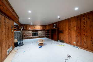 Unfurnished living room featuring a fireplace, carpet flooring, wood walls, and recessed lighting