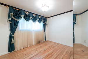 Unfurnished room featuring ornamental molding, baseboards, and wood finished floors
