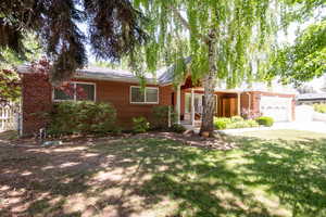 Single story home featuring brick siding, driveway, and a front yard