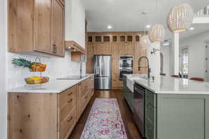 Kitchen with appliances with stainless steel finishes, a large island with sink, and decorative tile backsplash