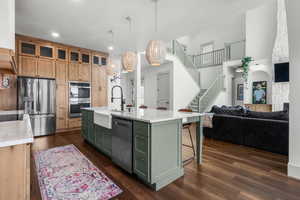 Kitchen featuring appliances with stainless steel finishes, green cabinetry and glass insert custom cabinets