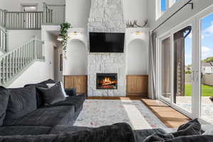 Main floor living room with a towering stone fireplace and stairway to second level