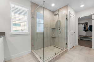 Bathroom featuring a stall shower, a walk in closet, baseboards, and recessed lighting