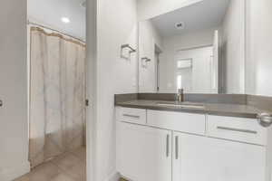 Bathroom with vanity, baseboards, tile patterned flooring, and a shower with shower curtain