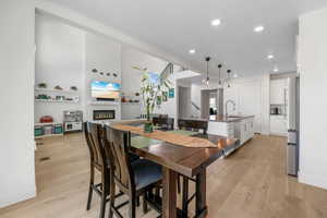 Dining room featuring light wood-type flooring, a glass covered fireplace, recessed lighting, baseboards, and a textured ceiling
