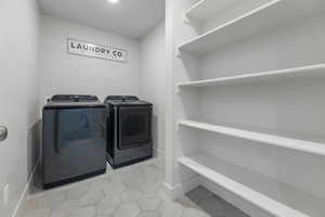 Laundry room with washer and clothes dryer, baseboards, and light tile patterned floors