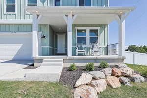Property entrance with covered porch, board and batten siding, and a garage