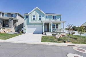 View of front of home featuring board and batten siding, covered porch, driveway, and a garage