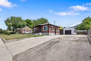 View of front of house featuring brick siding, an outbuilding, driveway, and a garage