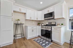 Kitchen featuring stainless steel appliances, light countertops, light wood-style flooring, tasteful backsplash, and recessed lighting