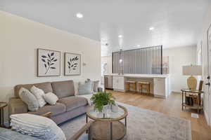 Living area with light wood finished floors and recessed lighting