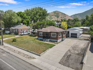 View of front facade with a detached garage, a front yard, a mountain view, and driveway