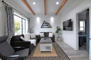 Living room with light wood finished floors, recessed lighting, and wood ceiling with exposed beams