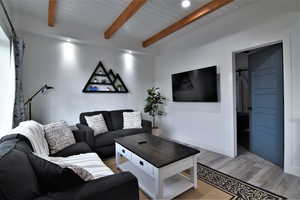 Living room with light wood-style floors, wood ceiling with exposed beams, baseboards, and recessed lighting