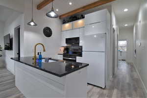 Kitchen with black appliances, a sink, beam ceiling, white cabinetry, and light wood-style floors