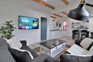 Living room with light wood-style floors, beam ceiling, and baseboards