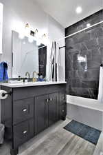 Bathroom featuring shower / tub combo with curtain, double vanity, recessed lighting, and wood finished floors