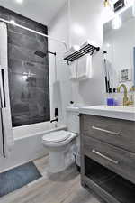 Bathroom with wood finished floors, shower / bath combo with shower curtain, vanity, and toilet