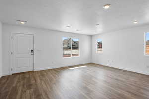Unfurnished room featuring wood finished floors, a textured ceiling, baseboards, and recessed lighting
