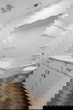 Bathroom with vanity, toilet, washtub / shower combination, wood finished floors, and recessed lighting