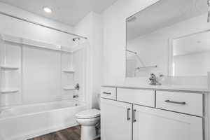 Full bath featuring vanity, toilet, wood finished floors, washtub / shower combination, and recessed lighting