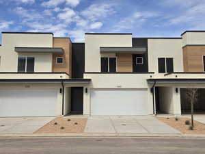 Modern home with a garage, stucco siding, and driveway