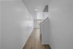 Hall featuring wood finished floors, a textured ceiling, and baseboards