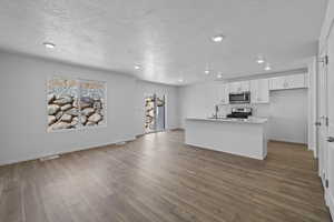 Kitchen featuring stainless steel appliances, a textured ceiling, white cabinets, light countertops, and a sink