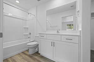 Full bath featuring toilet, vanity, shower / bathtub combination, and wood finished floors