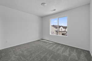 Spare room with dark carpet, baseboards, and a textured ceiling