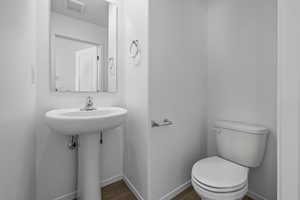 Half bathroom featuring toilet, baseboards, and wood finished floors