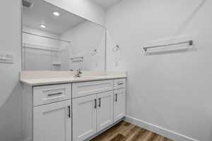 Full bathroom featuring wood finished floors, vanity, baseboards, a shower, and recessed lighting